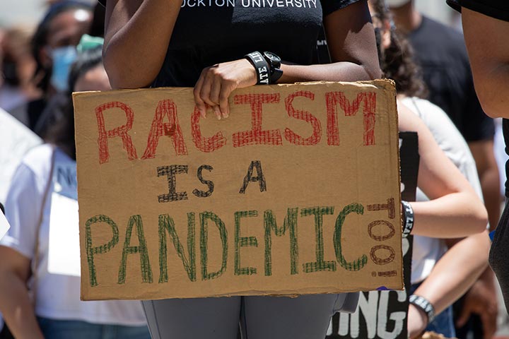 A sign reading "Racism is a pandemic too"