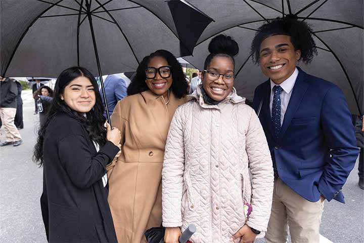 A group of three students and one staff member with umbrellas