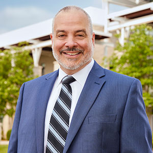 Joe Bertolino in white shirt and blue suit jacket in front of the Campus Center