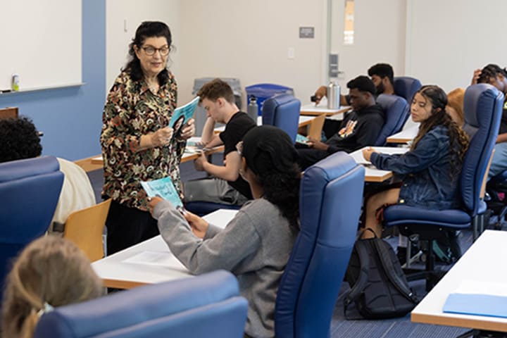 Gail Rosenthal stands in front of students in a new classroom with blue furniture