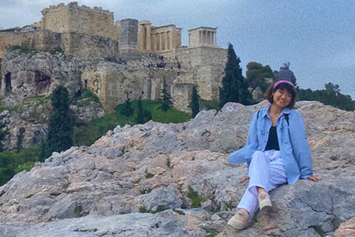 Eline Xia sitting on a rock in Greece