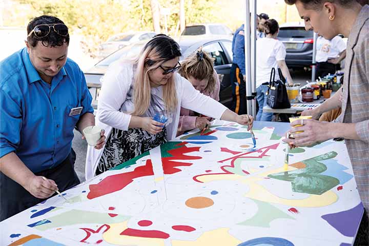 Community members add paint to a group art project