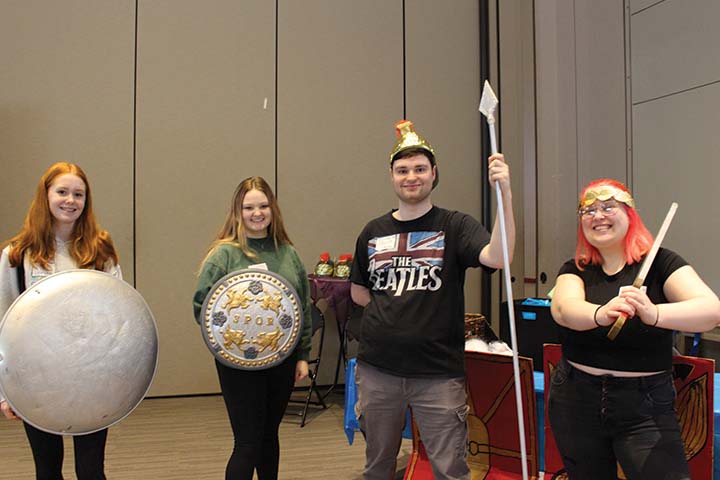 Four high school students with shields, spears and crowns