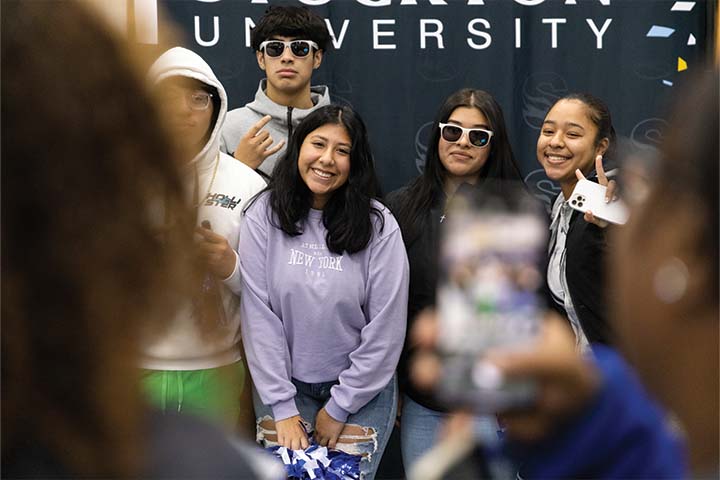 A group of students posing for a photo in front of a Stockton backdrop