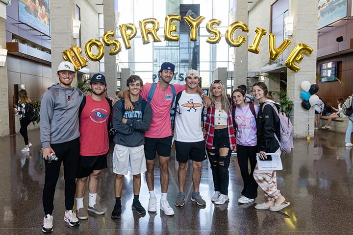 A group of students in front of balloons spelling out "Ospreys Give"