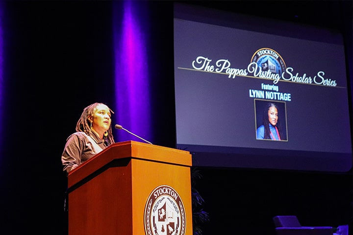 Lynn Nottage behind a podium addresses the crowd in the PAC