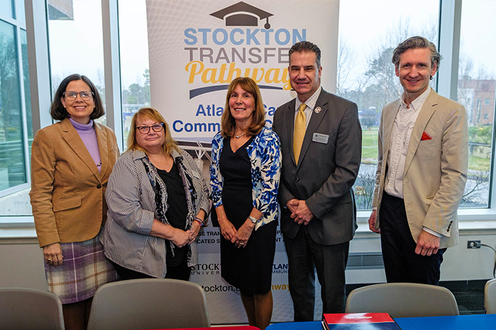 Faculty and staff from Atlantic Cape and Stockton pose for a group photo in front of a Transfer Pathways banner