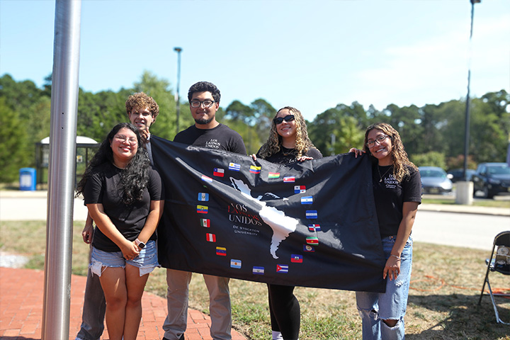 Five Stockton students hold up the Pan American flag prior in the Arts & Sciences Circle