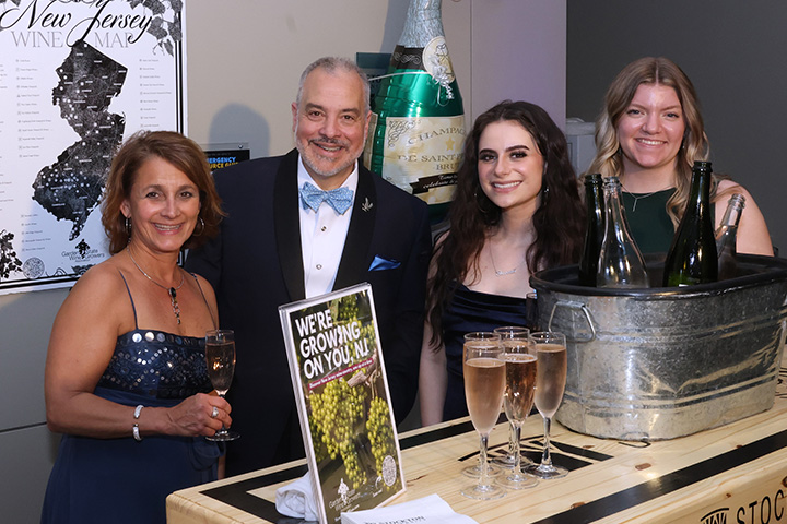 Faculty and students in fancy attire behind a wine bar at the Scholarship Gala