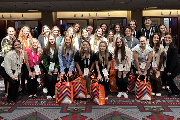 Fifty six students in the Occupational Therapy program take a group photo in the hall of the conference event space