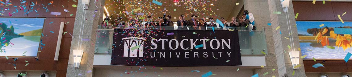 The Stockton University banner hangs in the Campus Center Grand Hall while confetti falls through the air