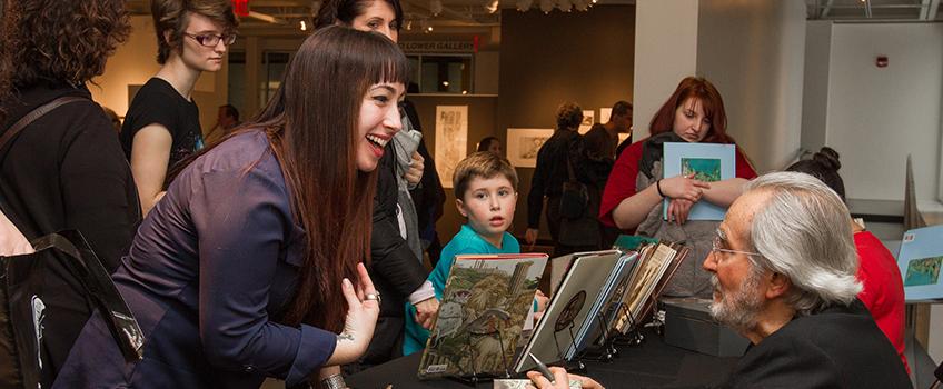 Artitst signing books in the art gallery