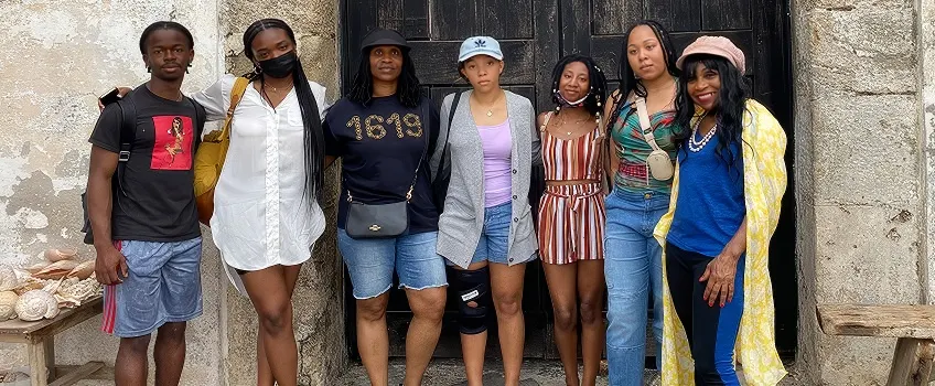 Stockton students studying abroad posing for a photo against a rustic wall.