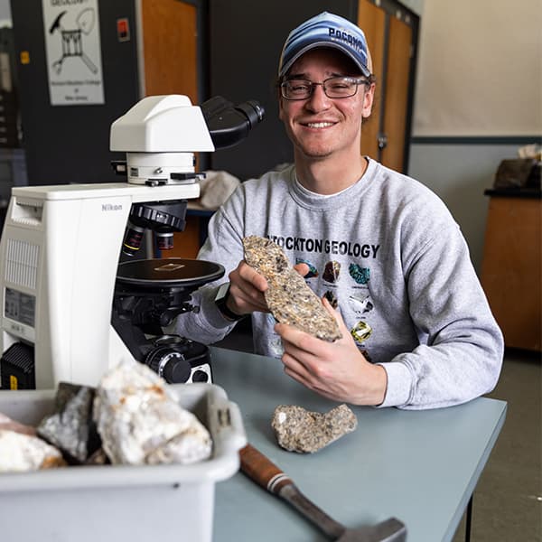 Joseph Rosal holding a rock in a laboratory