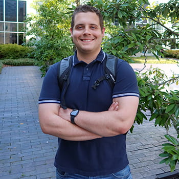 Ryan Bowie smiling for the camera in front of the academic spine