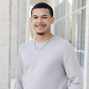 Sean Lopez, smiling for the camera in front of the Campus Center