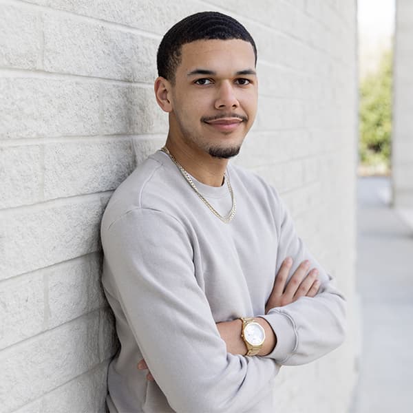 Sean Lopez standing in front of the Campus Center with his arms crossed and his back against the wall