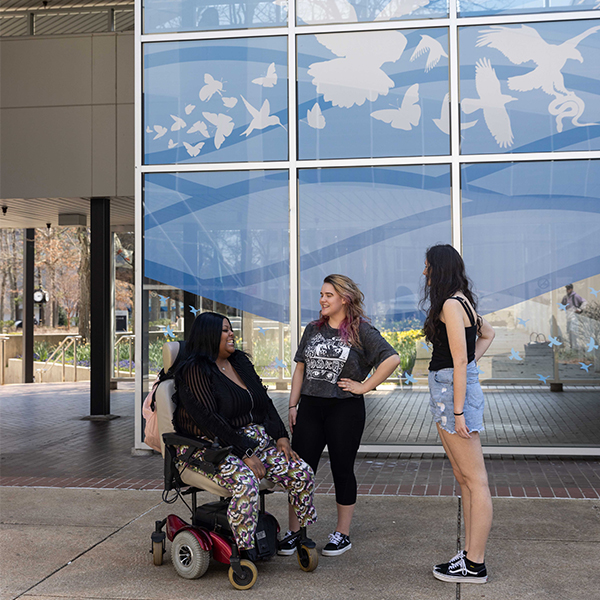 Tierra Houston, chatting with friends outside of a mural outside of K-wing