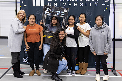 Students posing with a "Choose Stockton" sign during Latino Visitation Day