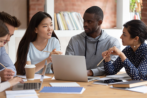 A stock image of colleagues around a table discussing work