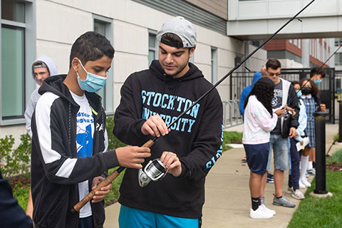 Student showing middle school student how to hold a fishing line