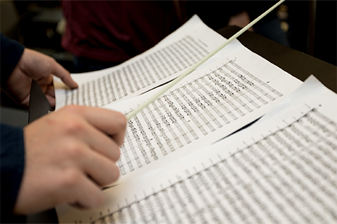 A stock image of a conductor over a sheet of music