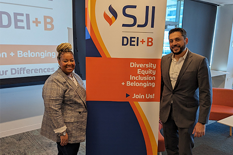 Walead and his friend posing next to a sign that says "SJI DEI+B Summit"