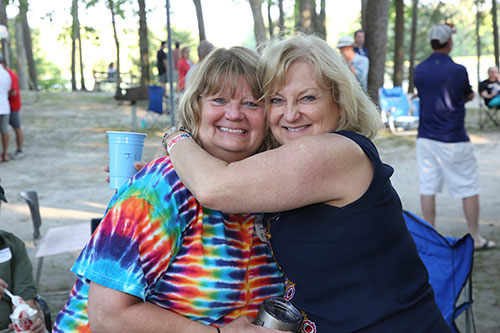 2 alumni at Spring Bash hugging outdoors