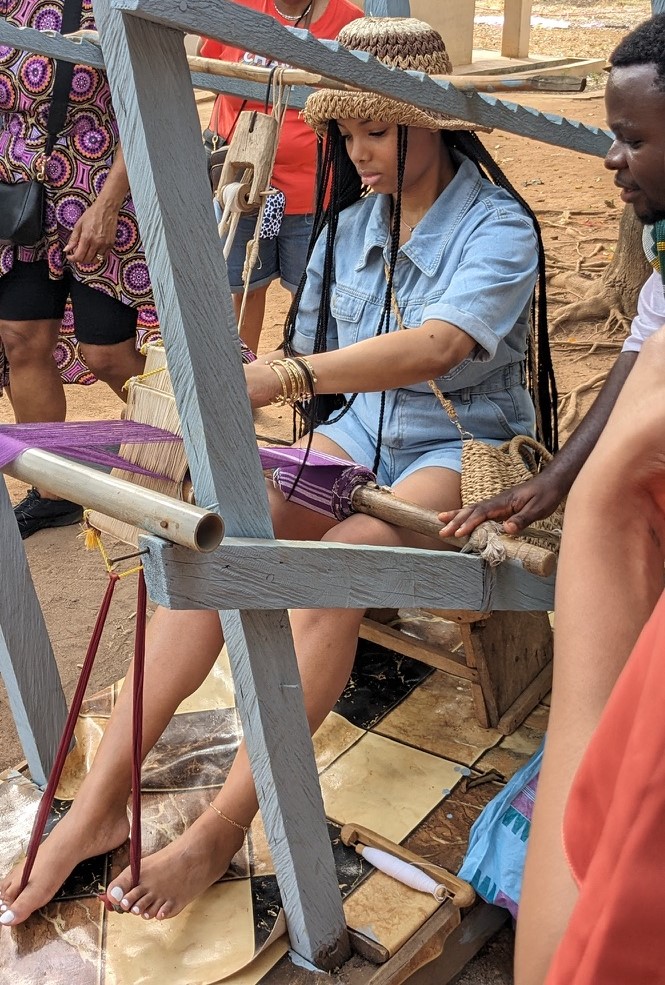 Student weaving outdoors.