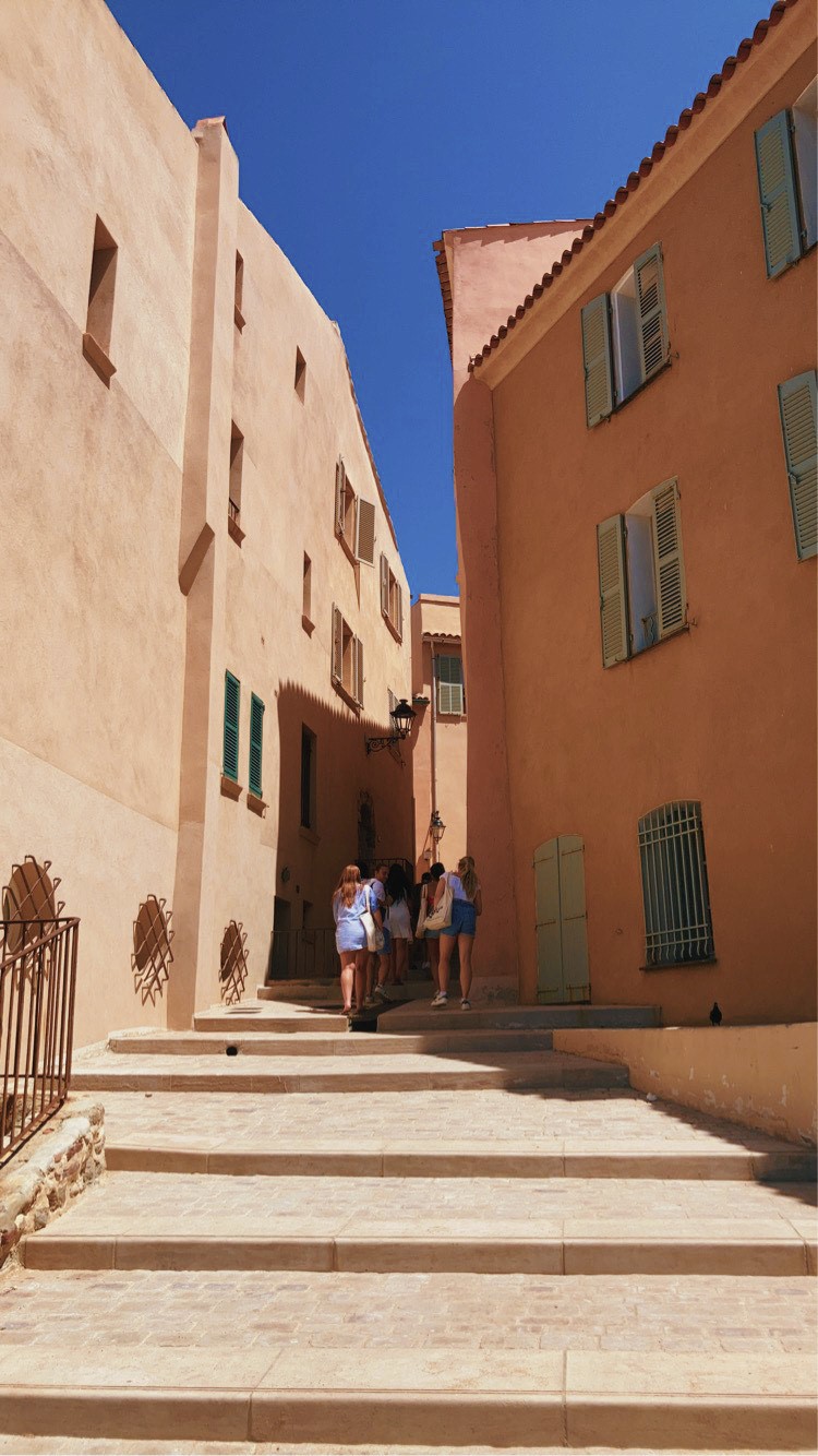 Shades of orange hues run through two sides of buildings in an outdoor, city corridor.