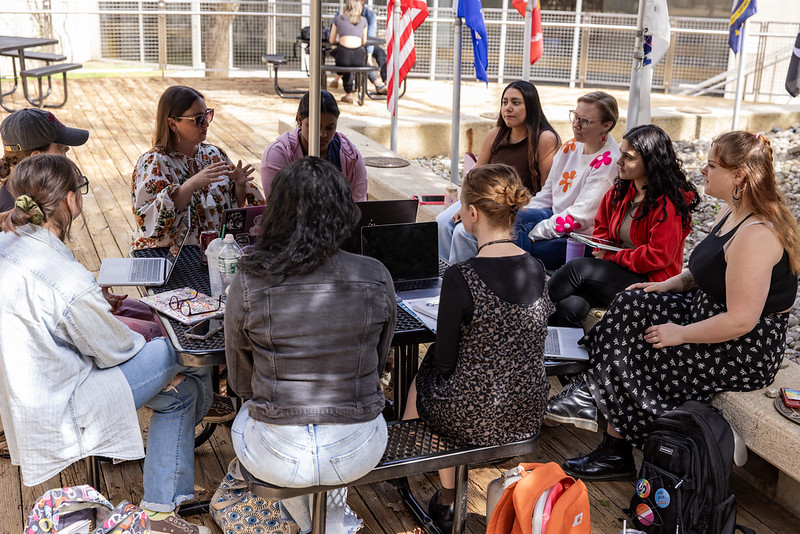 Students sitting in an outdoor table engaged in learning.