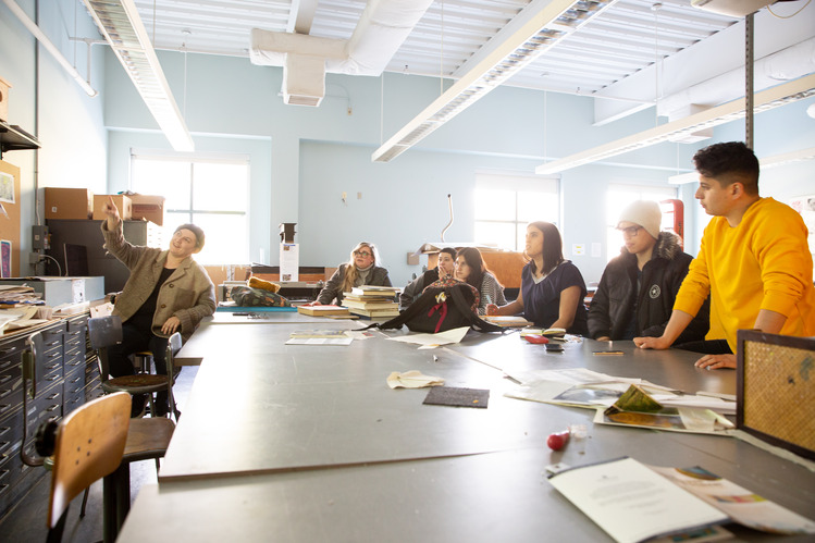 Students gathered around a table actively engaged in learning.