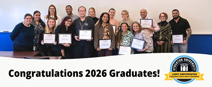 Group of program graduates instructors and administrators smile at the camera. Graduates hold their framed certificates.