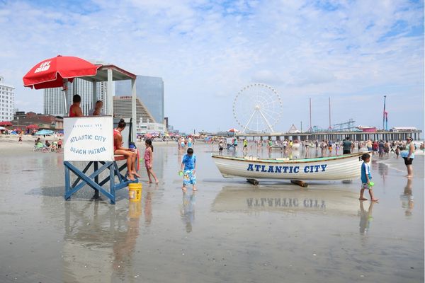 View from Atlantic City beach looking toward steel pier, children playing, lifeguard stand and rescue boat in foreground 
