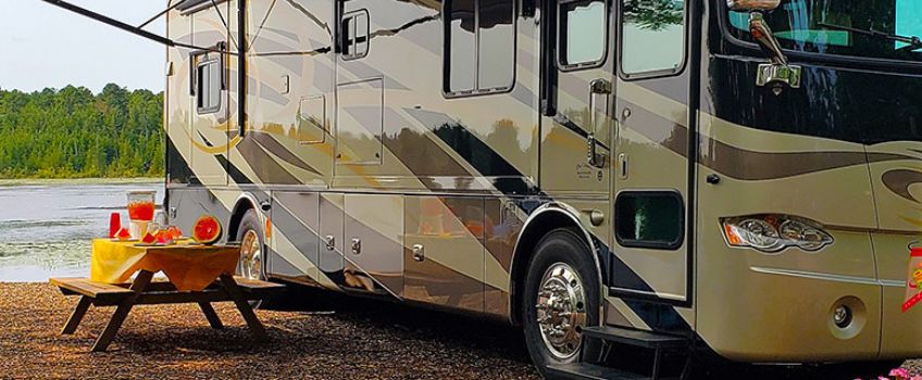 NJCOA With Permission - RV parked beside a lake, picnic table with colorful fruit and drinks