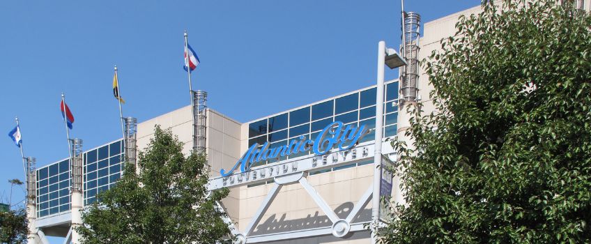 Facade of Atlantic City Convention Center by day, bright blue sky flags blowing in wind 