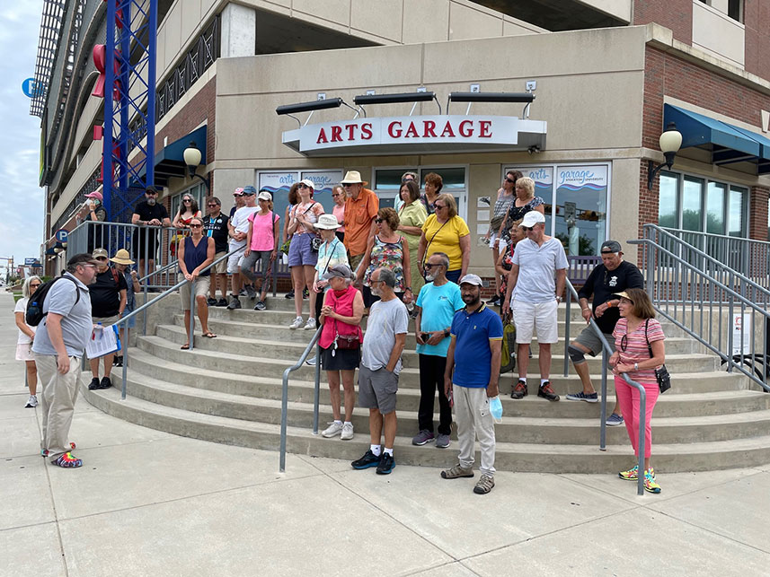 Participants stop on steps of Noyes Arts Garage of Stockton University to listen to tour guide Levi Fox. 