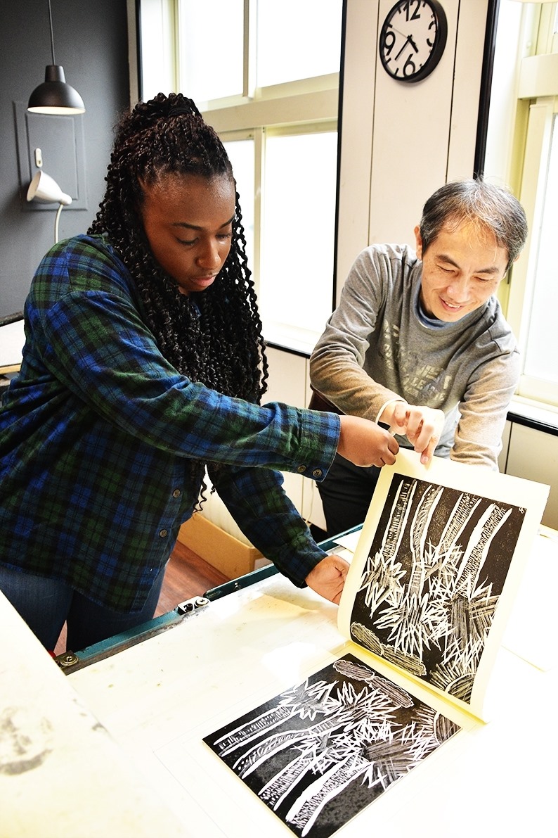 student showing artwork to professor