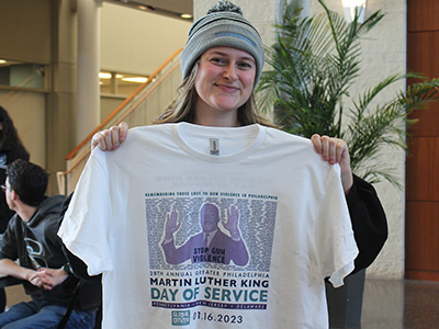 Student Senate president holding up a MLK Day t-shirt that was given to volunteers