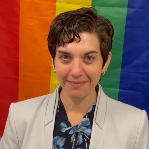 Haley Baum in front of a rainbow flag