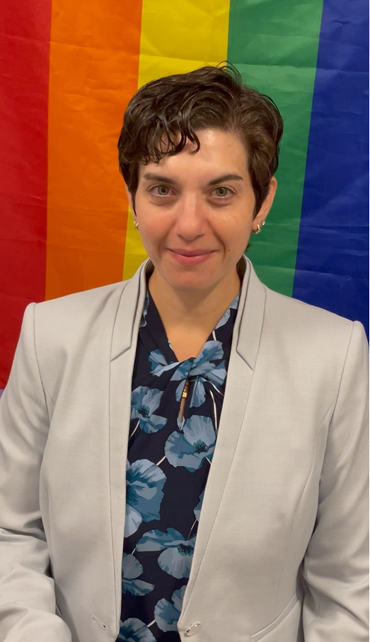 Haley Baum in front of a rainbow flag