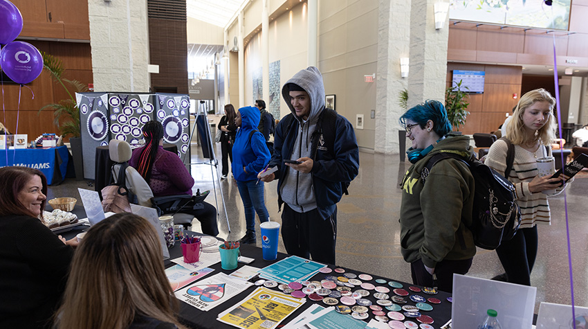 Students surrounding the WGSC table during the International Women's Day celebration.