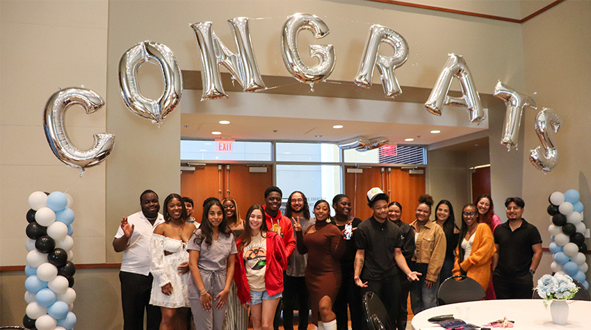 The graduates in front of a balloon banner that says "Congrats"