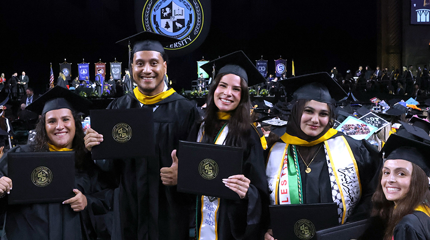 Graduates celebrating and posing for a photo in Jim Whelan Boardwalk Hall