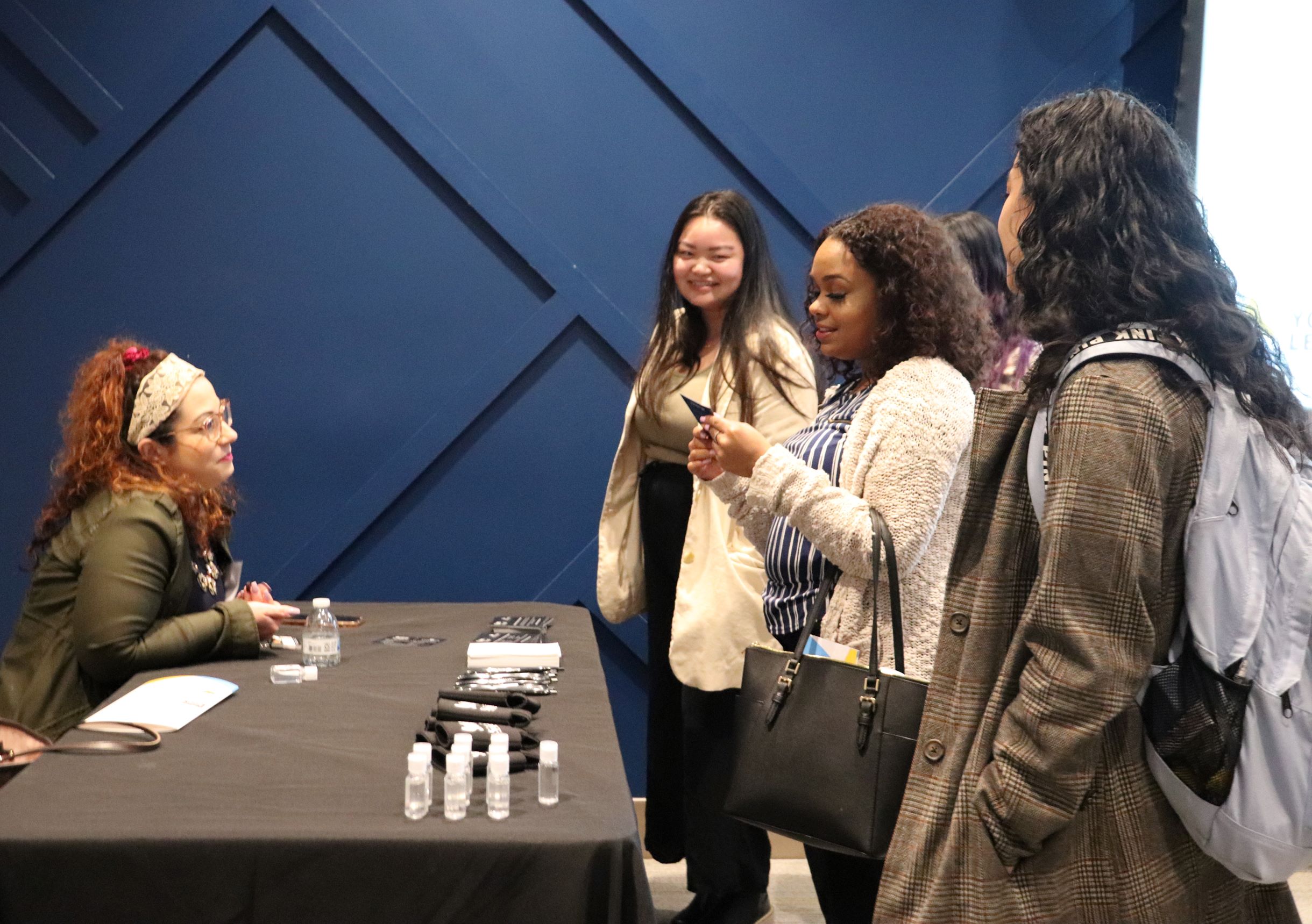 Kimberly Mendez, a junior Business Studies/Marketing major with a minor in Cannabis Studies, was excited for the chance to chat with local businesses in hopes of finding an internsship for next year at the Young Leaders Expo. She stands in center with friends speaking to a representative from Spencer's and Spirit Halloween.