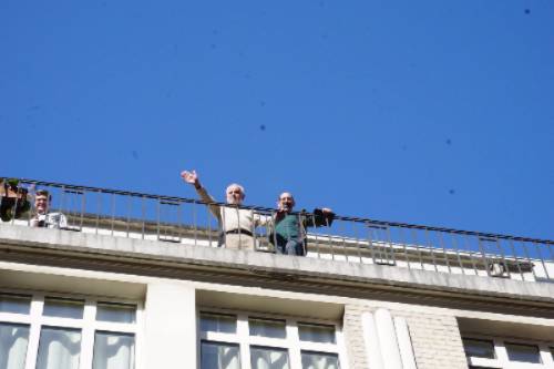 Holocaust survivor Daniel Kochavi waves from balcony.