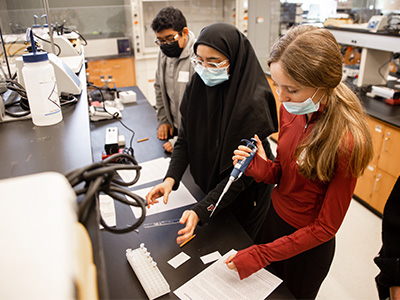 A Stockton student (middle) leading a science experiment