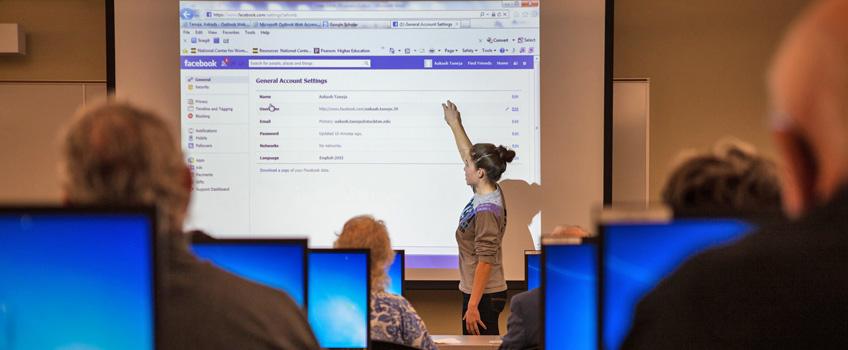 Student demonstrating Facebook to a group of seniors citizens