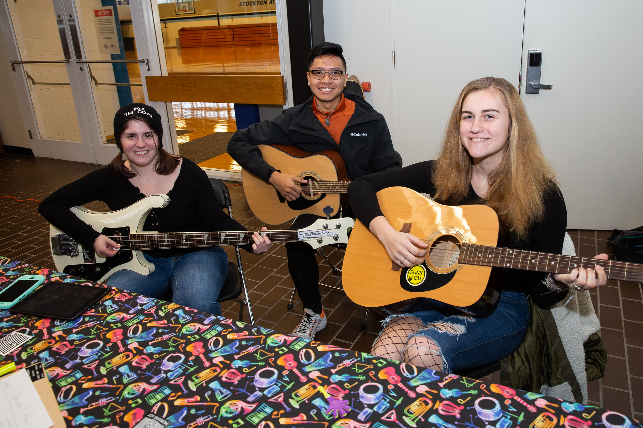 three students playing guitar