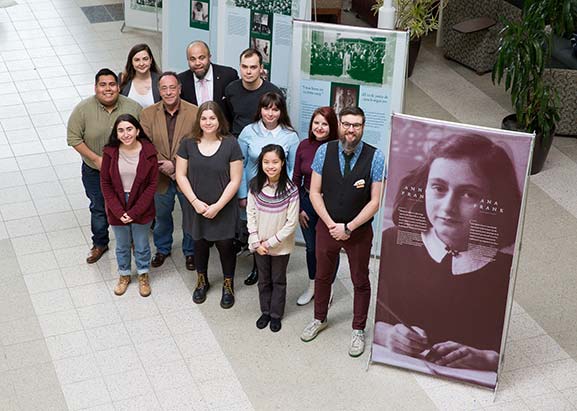Students and staff stand in front of Anne Frank exhibit
